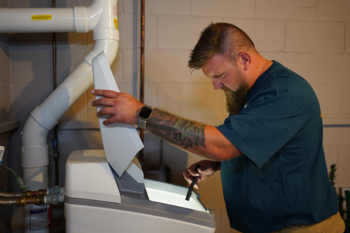 Plumber servicing a water softener system, showing professional installation as part of overall water softener cost.
