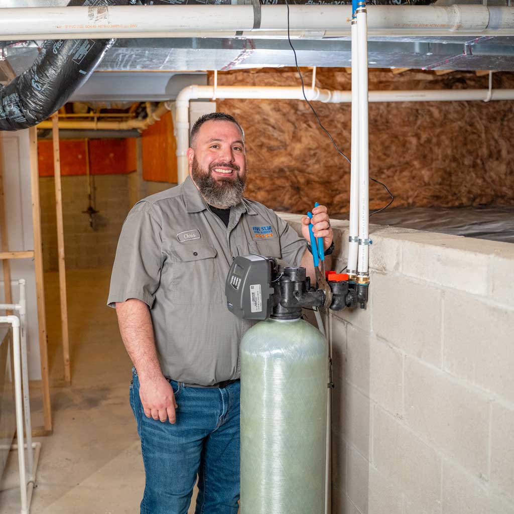 ive Star Home Services plumber with a newly installed carbon filter system in a residential basement.