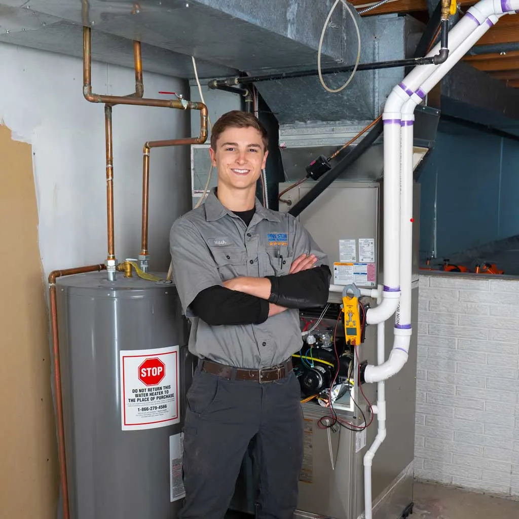 furnace technician standing next to furnace and water heater